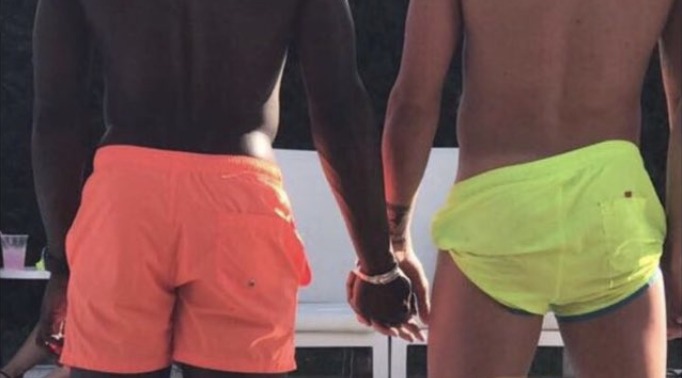 Two men holding hands by a poolside setting